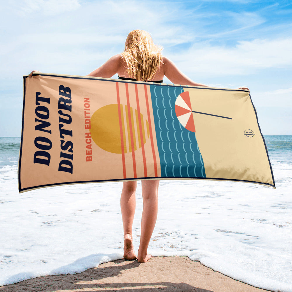The Do Not Disturb Beach Towel, held up on the beach
