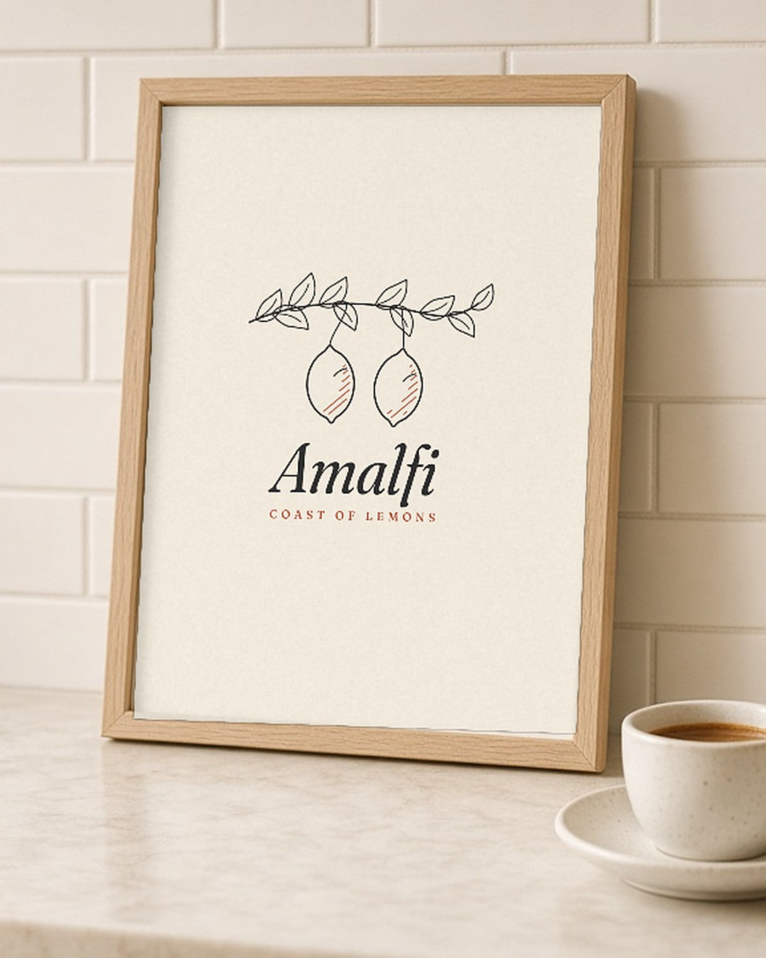 The Amalfi Art Print, framed on a kitchen counter next to a bowl of lemons and an espresso cup