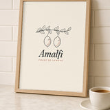 The Amalfi Art Print, framed on a kitchen counter next to a bowl of lemons and an espresso cup