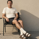 The Amalfi Socks in Cream, man relaxing on a chair against a sunny wall, socks worn with sandals