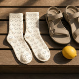 The Amalfi Socks in Cream, a pair laid flat on wooden slats next to sandals and a lemon