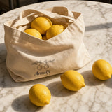 The Amalfi Tote in Oyster, tipped over on a café table with lemons rolling out beside an espresso