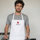 The Head Chef Apron in White, man in a kitchen holding a frying pan and a wooden spatula