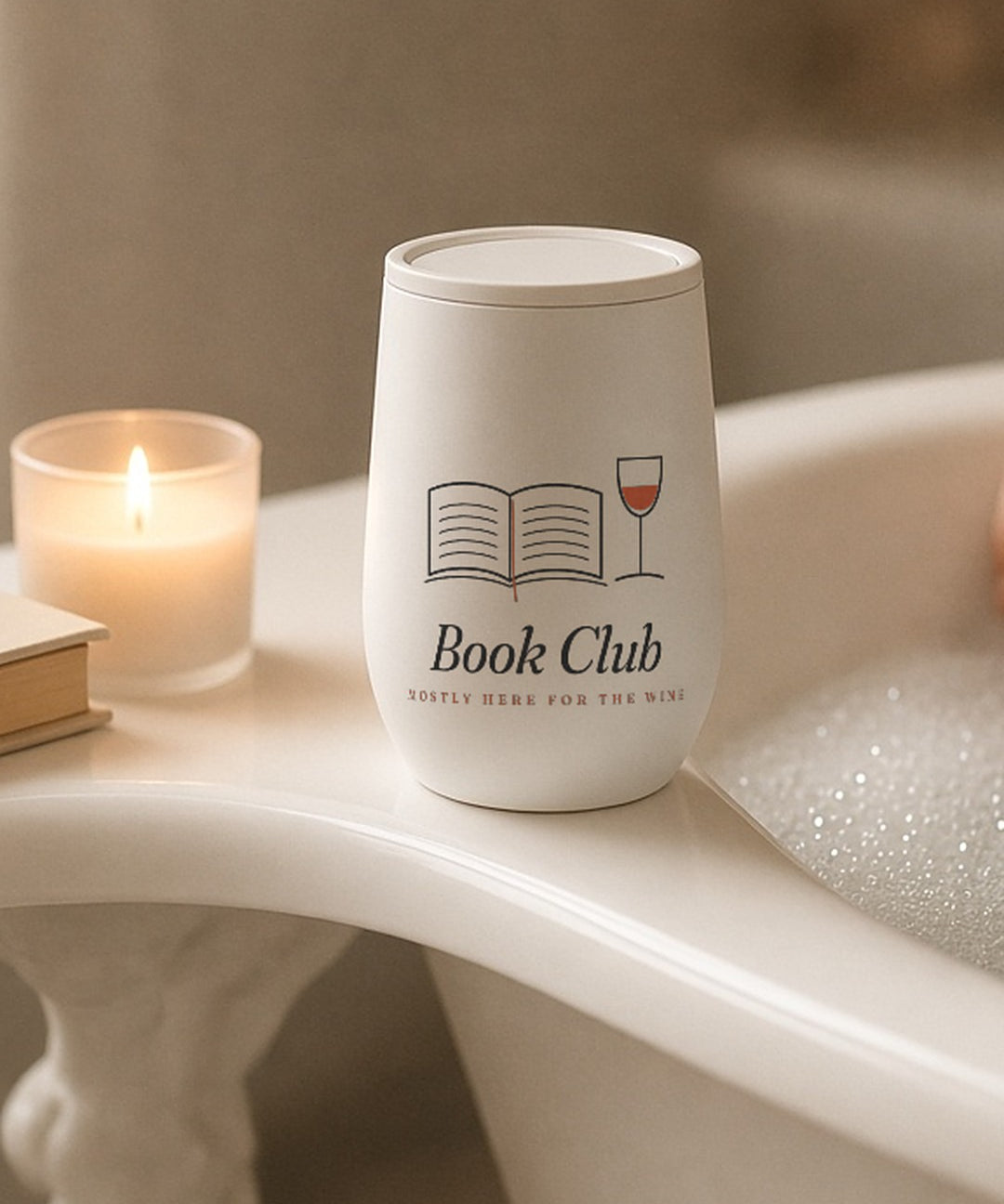 The Book Club Wine Tumbler on the edge of a bathtub with a candle and a book