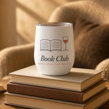 The Book Club Wine Tumbler in White, tumbler on a stack of books by an armchair