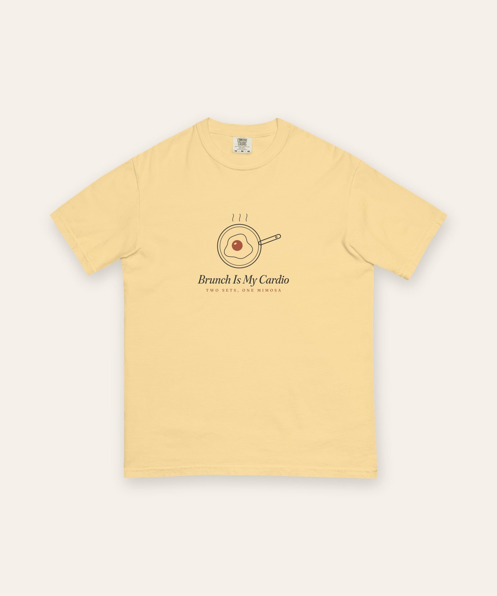 The Brunch Is My Cardio Tee in Butter, flat lay front, product shot on cream