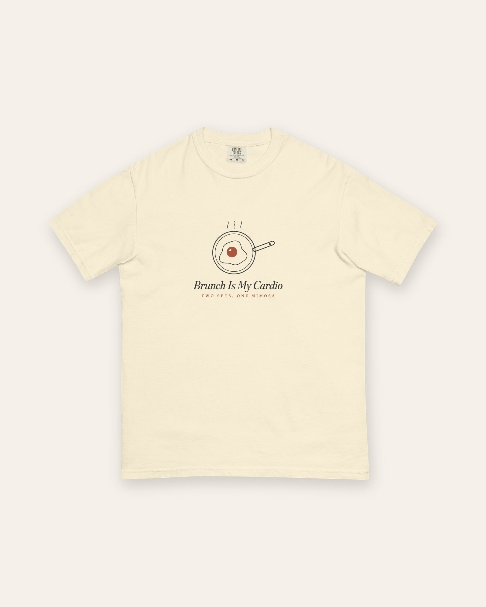 The Brunch Is My Cardio Tee in Ivory, flat lay front, product shot on cream