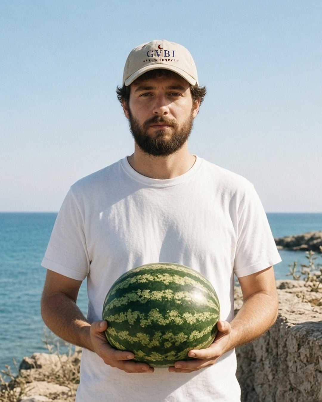 The House Dad Hat in Stone, man by the sea holding a watermelon in both hands