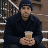 The Do Not Disturb Beanie in Navy, worn on a snowy stoop with an iced coffee