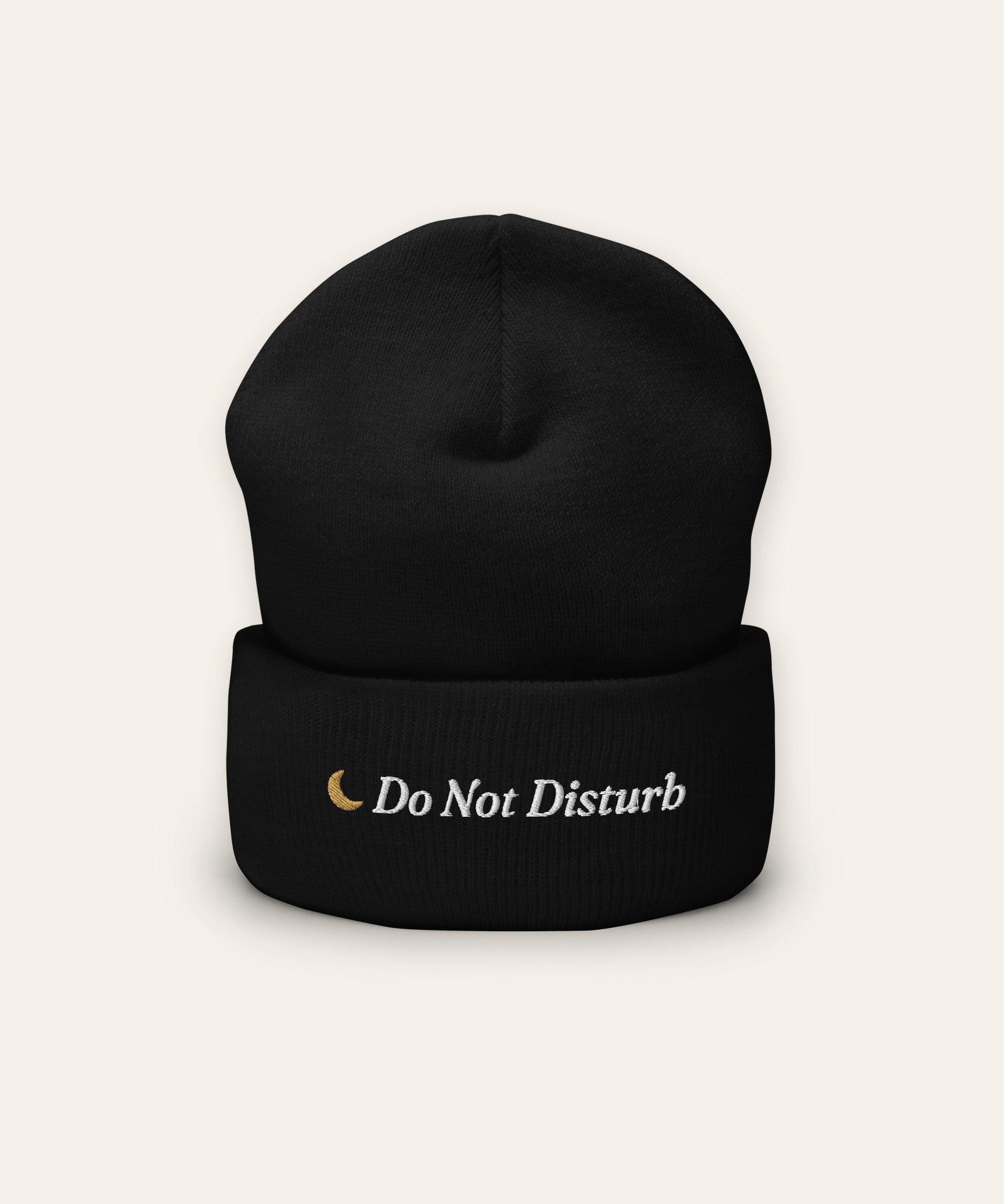 The Do Not Disturb Beanie in Black, flat lay front, product shot on cream
