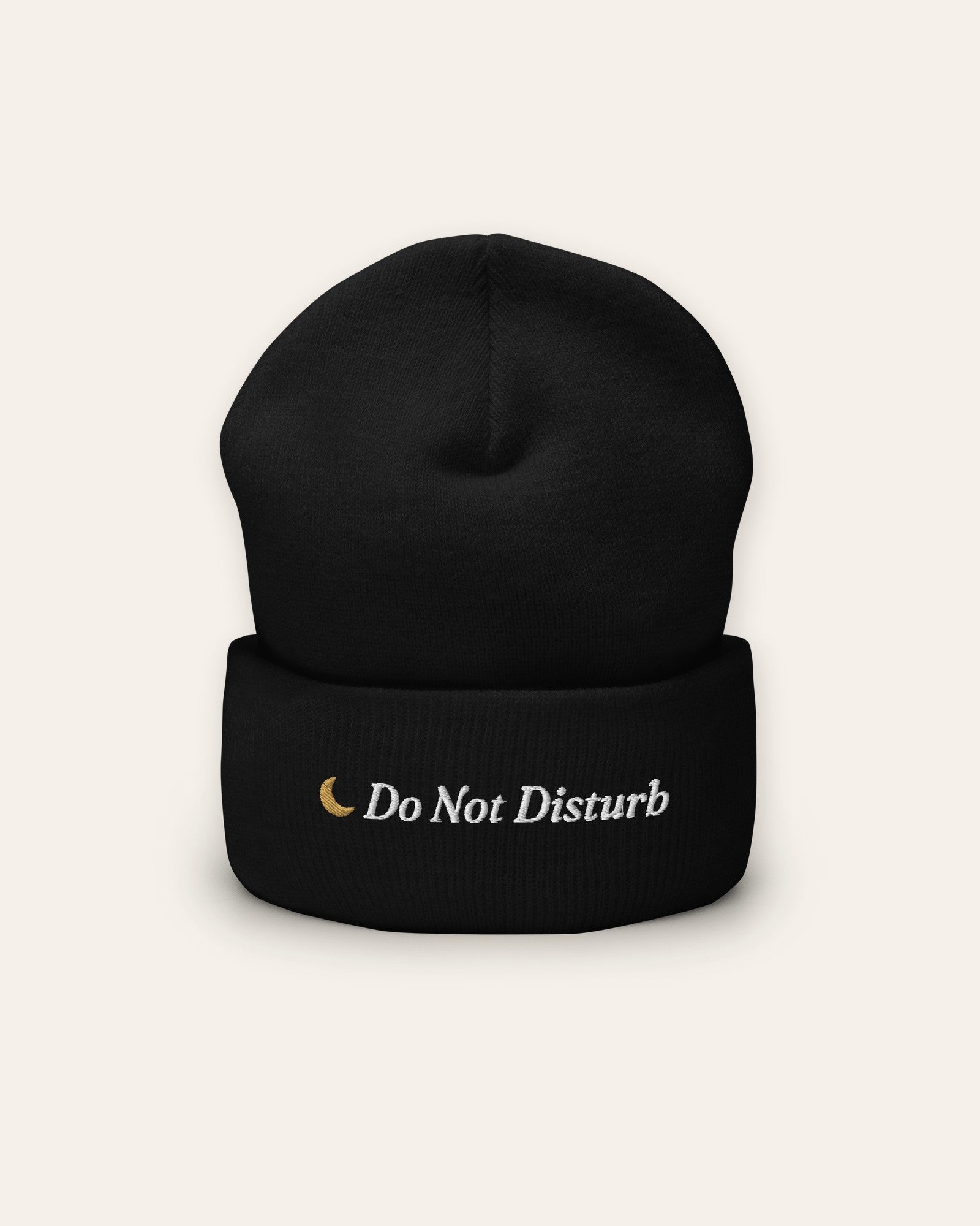 The Do Not Disturb Beanie in Black, flat lay front, product shot on cream