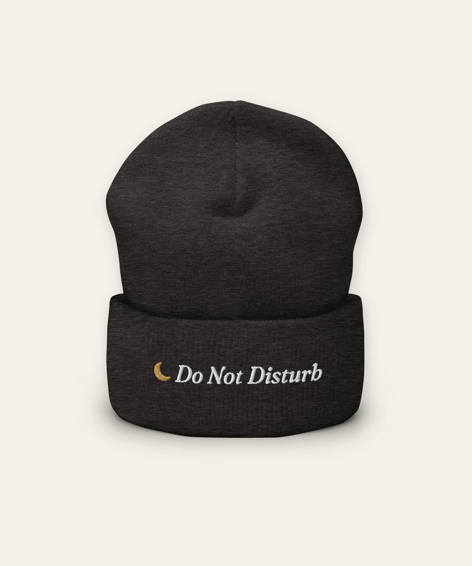 The Do Not Disturb Beanie in Dark Grey, flat lay front, product shot on cream