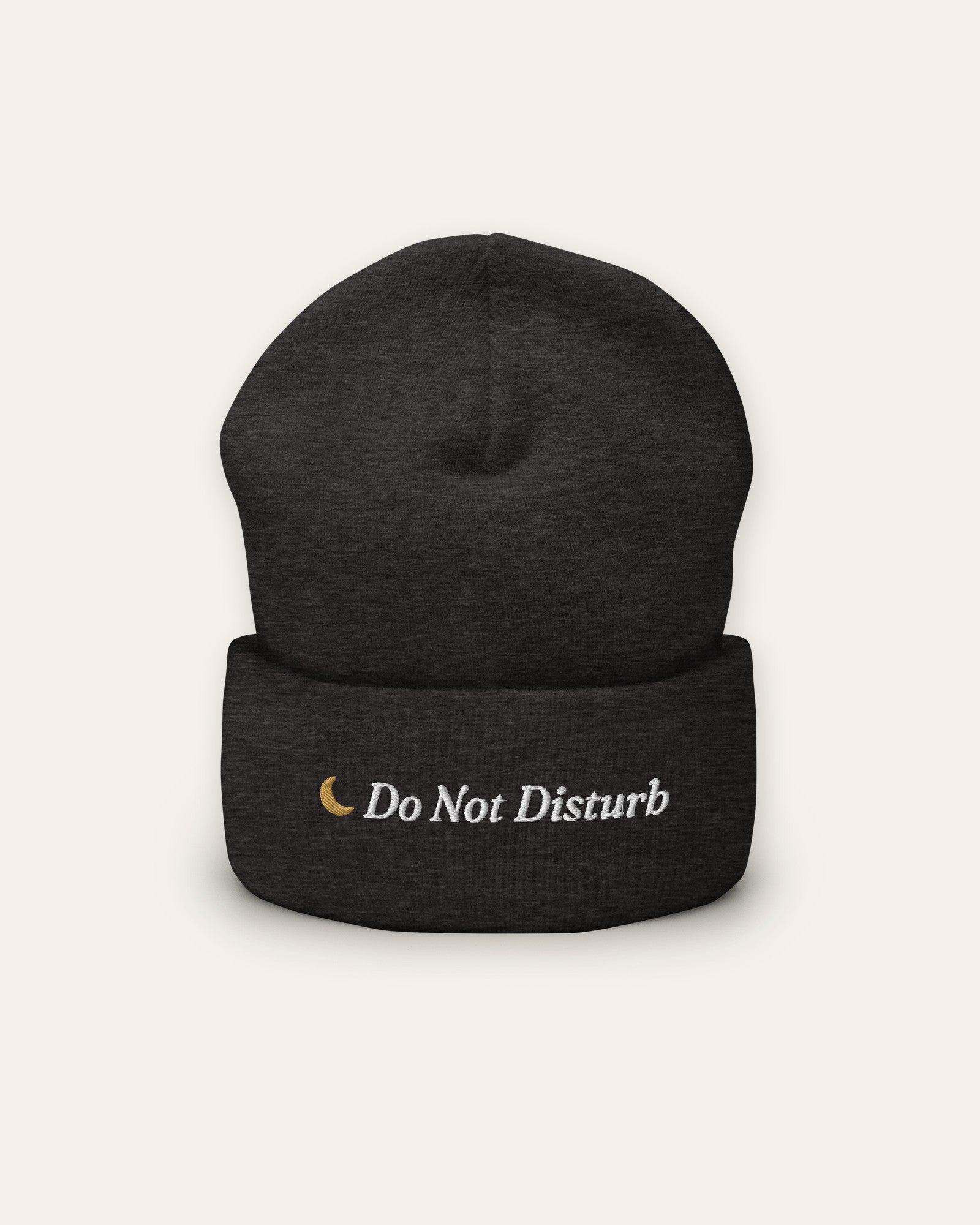 The Do Not Disturb Beanie in Dark Grey, flat lay front, product shot on cream