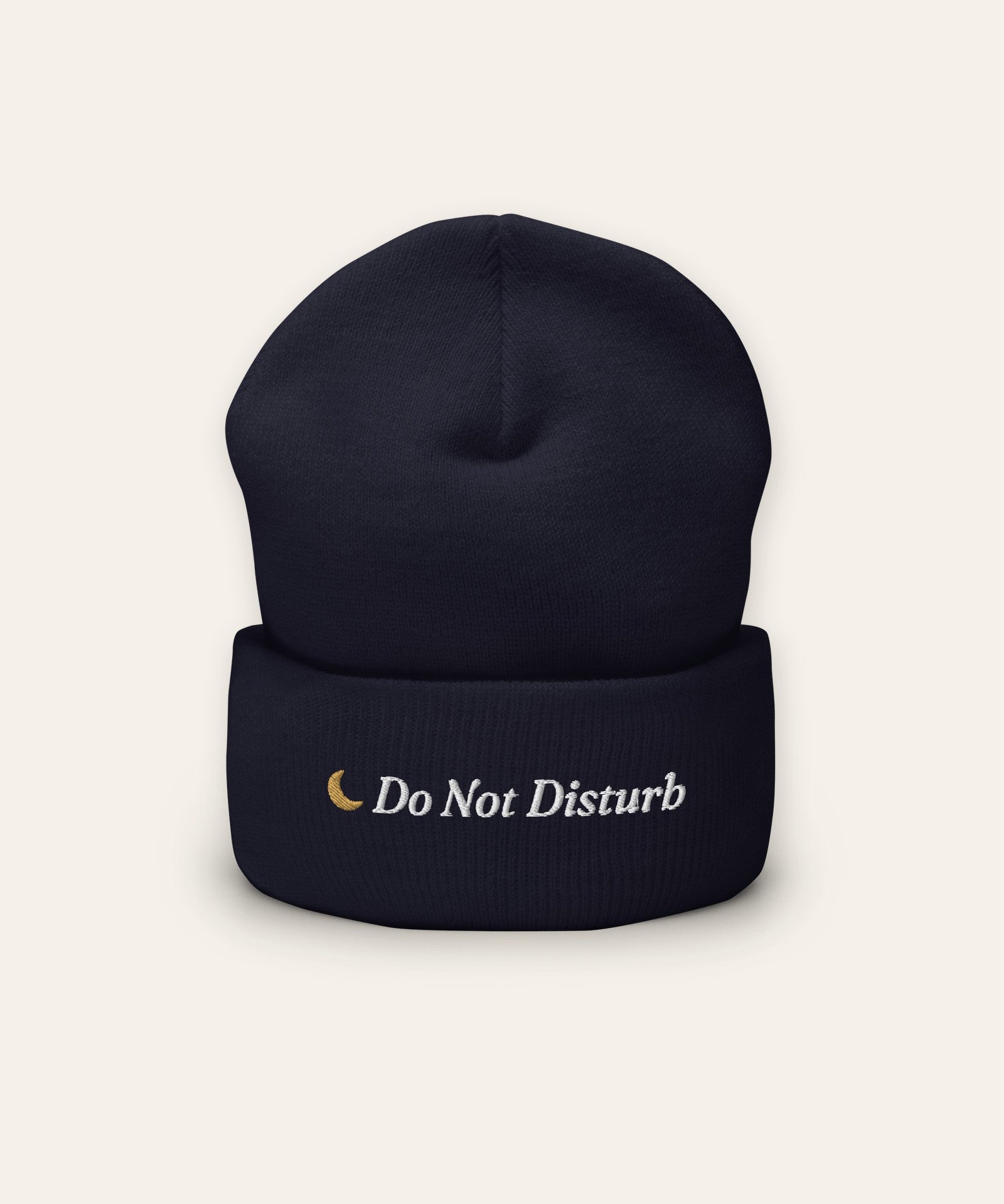 The Do Not Disturb Beanie in Navy, flat lay front, product shot on cream