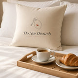 The Do Not Disturb Pillow on crisp white bedding with a breakfast tray