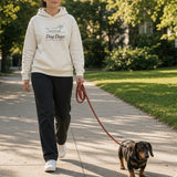 The Dog Days Hoodie in Bone, worn by a woman being pulled along the sidewalk by a dachshund