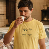 The Extra Virgin Tee in Butter, worn by a man solemnly sniffing a cup of olive oil at a deli counter