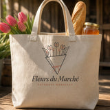 The Fleurs du Marché Tote in Oyster, tote on a market table with pink tulips, a baguette and a jar of honey