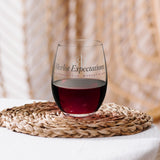 The Merlot Expectations Wine Glass with red wine on a woven placemat