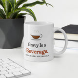 The Gravy Is a Beverage Mug on a desk next to a keyboard and a plant