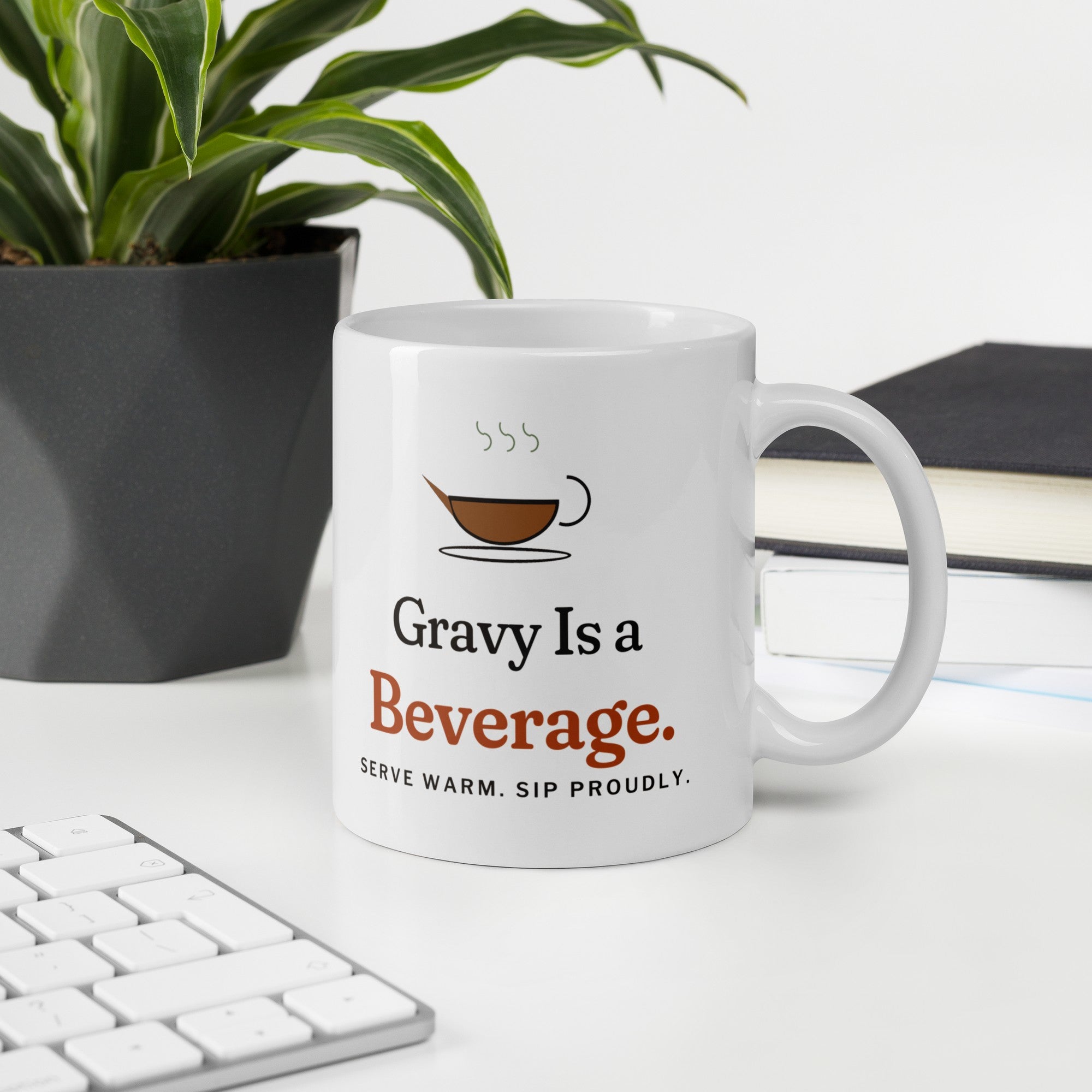 The Gravy Is a Beverage Mug on a desk next to a keyboard and a plant
