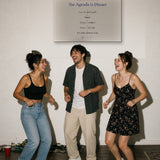 Three friends dancing at a house party under The Agenda Is Dinner Print hanging on a white wall
