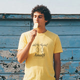 The Amalfi Tee in Butter, eating a popsicle against a peeling blue wall