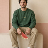 The Social Club Crewneck in Forest Green, sitting on a stucco ledge with a slice of watermelon