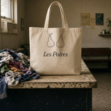 The Les Poires Tote on a laundromat folding table next to a pile of laundry