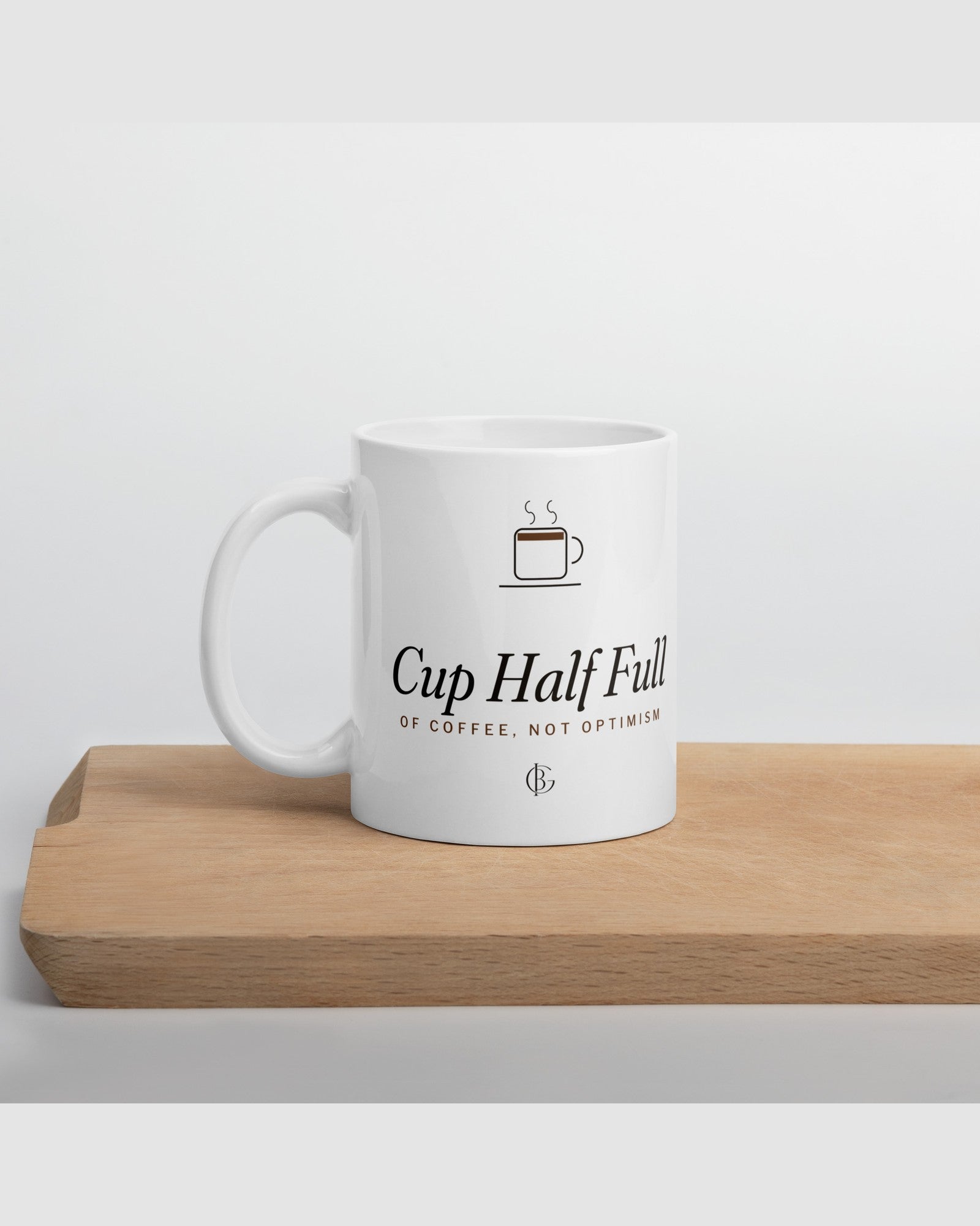 The Cup Half Full Mug in White, styled on a table