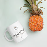 The Cup Half Full Mug in White, styled on a table