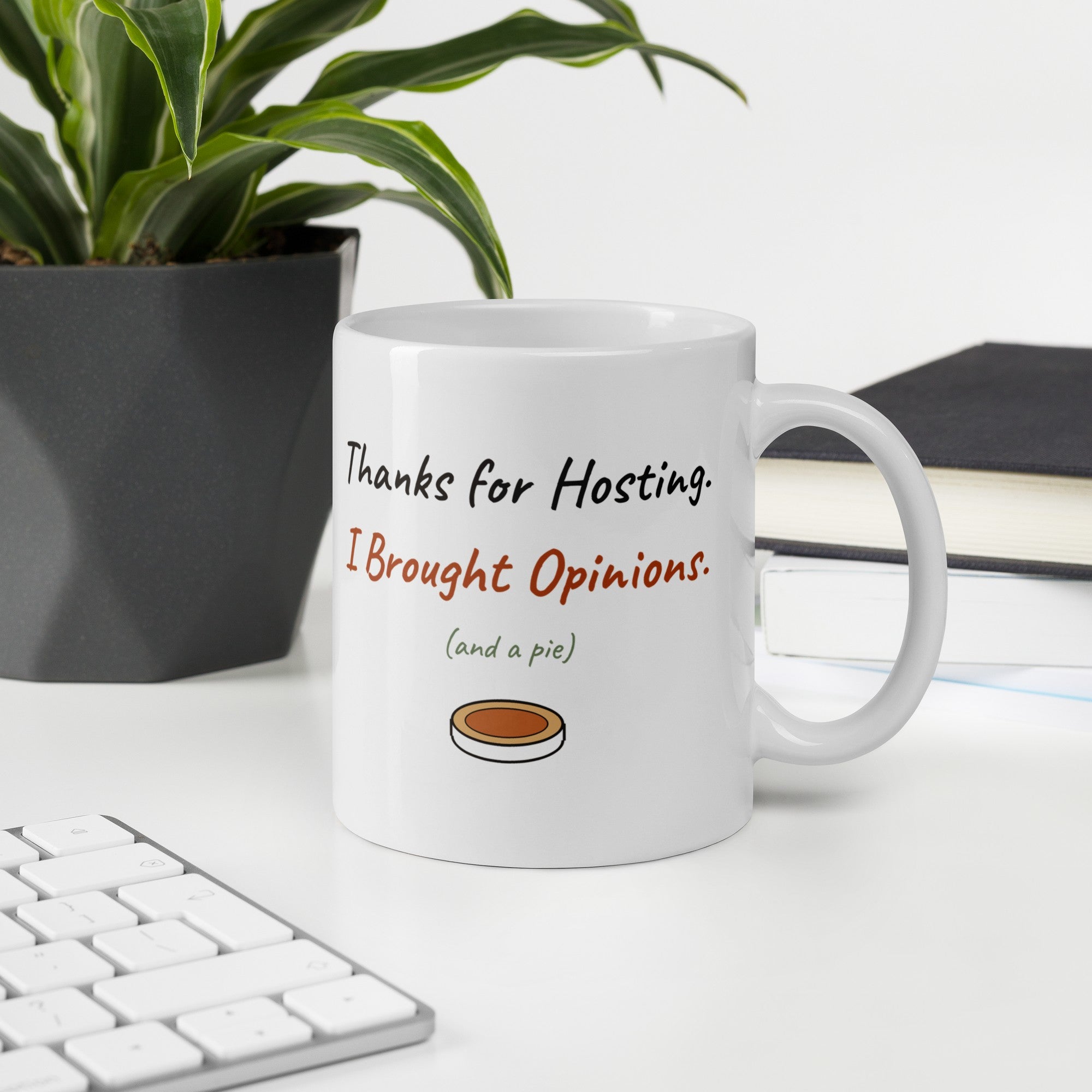 The Thanks for Hosting Mug on a desk next to a keyboard and a plant