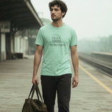The Hot Mess Express Tee in Chalky Mint, man walking down an empty commuter platform carrying a duffel, hazy light