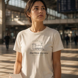 The Hot Mess Express Tee in Ivory, a woman (20s) in Ivory staring up at a departures board where every train says DELAYED