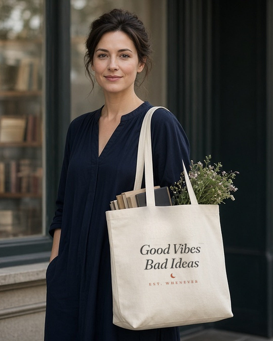 The House Tote in Oyster, oyster tote on a woman's shoulder outside a bookstore window, books and greens sticking out