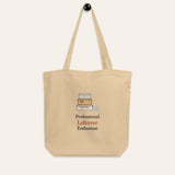 The Professional Leftover Enthusiast Tote hanging on a hook against a cream wall