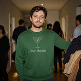 The Dirty Martini Crewneck in Forest Green, man in the Forest Green crewneck holds an armful of coats at a house party, guests behind, flash