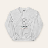 The Moka Crewneck in Ash, flat lay front, product shot on cream