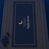 The Night Swim Beach Towel laid out on a dock with flip-flops and a flashlight, seen from above