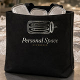The Personal Space Tote in Black, the Black tote at a fish counter with a few sardine tins inside