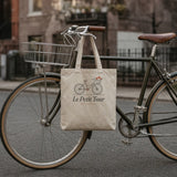 Le Petit Tour Tote in Oyster, tote hanging flat from the handlebar of a vintage bike on a brownstone street