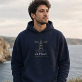 Le Phare Hoodie in Navy Blazer, man on a coastal clifftop path, overcast evening, hands in the hoodie pocket