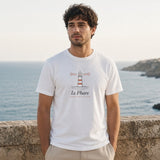 Le Phare Tee in White, man standing at a stone seawall above a rocky coast, hands in pockets