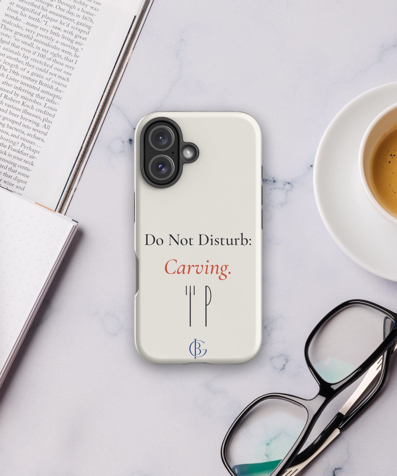 The Do Not Disturb Carving Phone Case on a desk with coffee