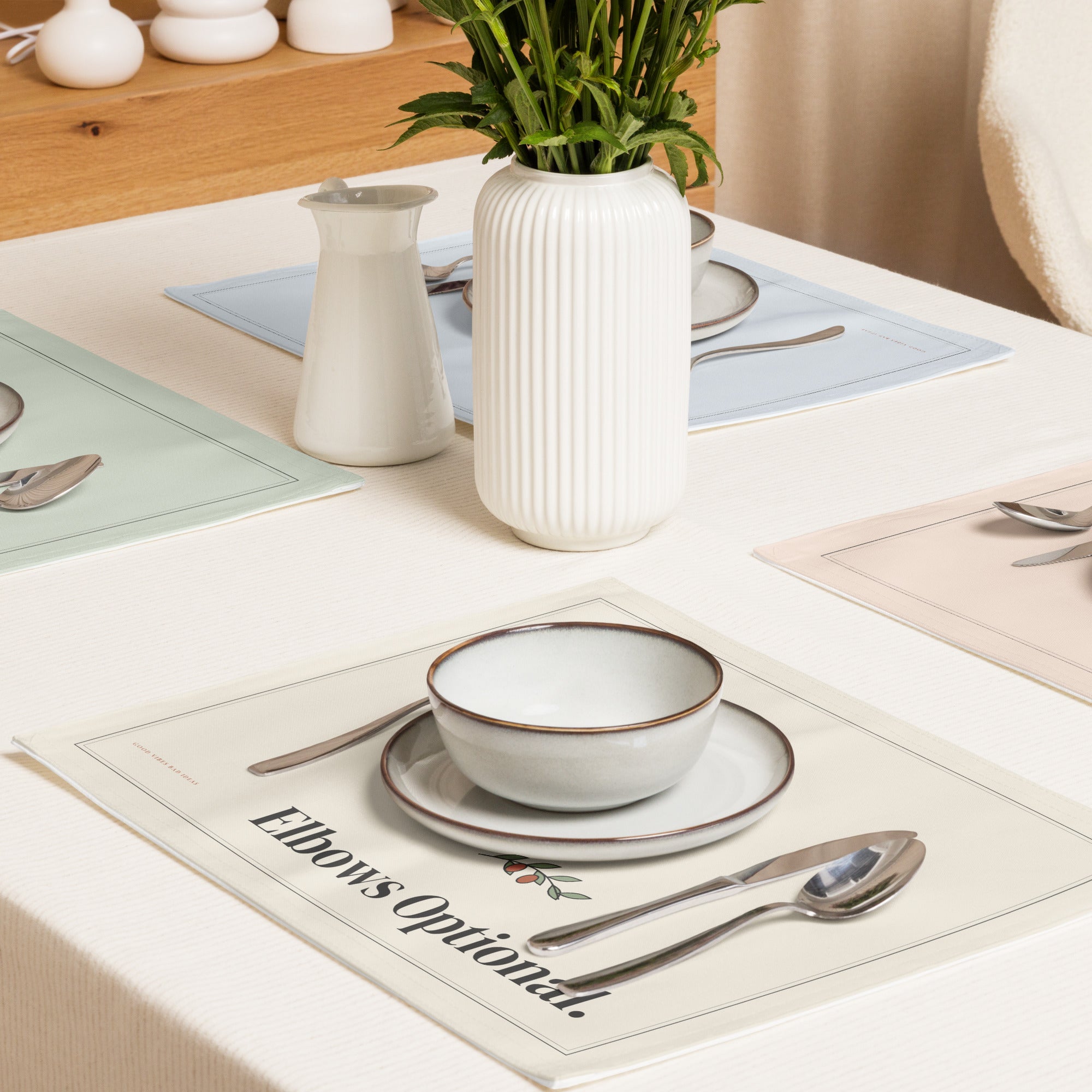The placemats on a dinner table with stoneware bowls and a vase