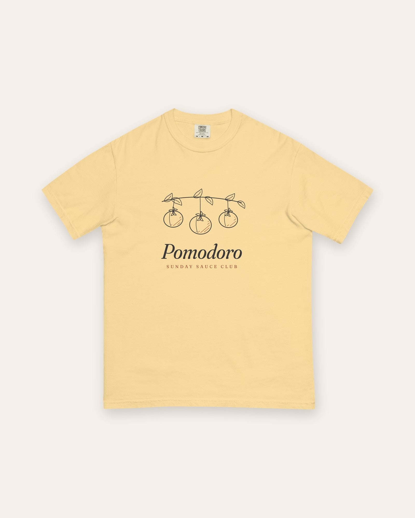 The Pomodoro Tee in Butter, flat lay front, product shot on cream