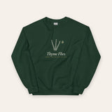 The Thyme Flies Crewneck in Forest Green, flat lay front, product shot on cream