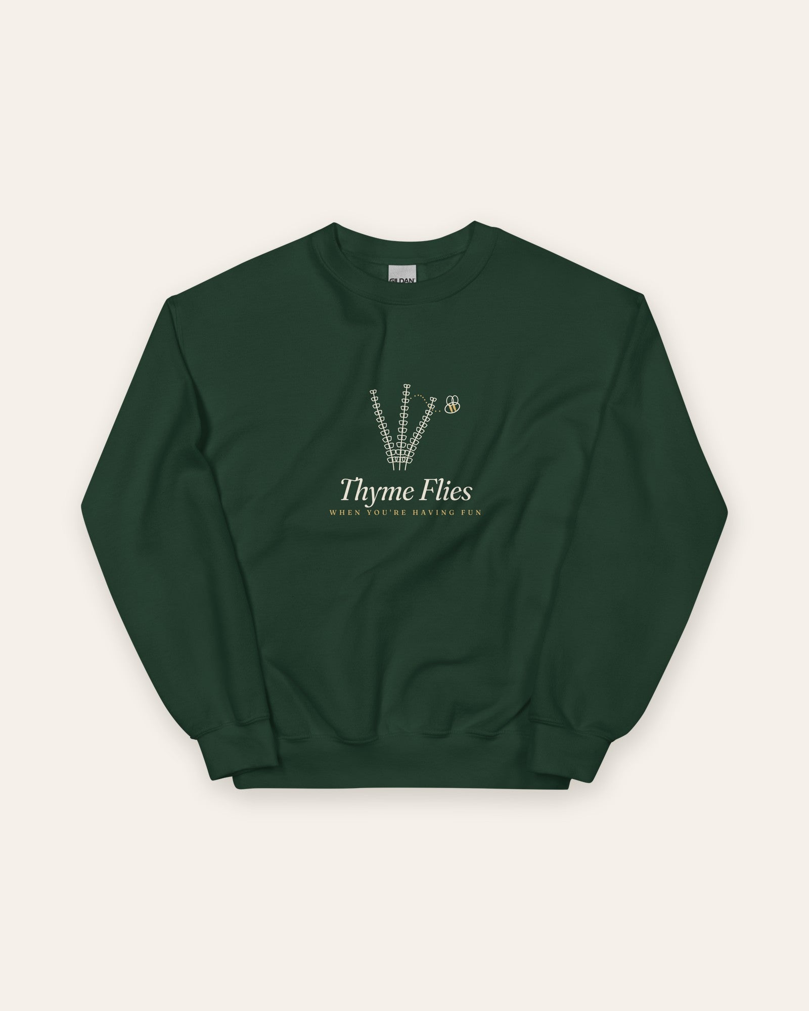 The Thyme Flies Crewneck in Forest Green, flat lay front, product shot on cream