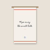 The Small Talk Kitchen Towel hanging from a wooden rail