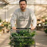 The Watering Can't Crewneck in Ash, a man in Ash pushing a cart full of plastic plants